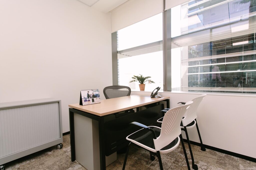Modern office space in Dubai featuring a sleek desk, ergonomic chairs, natural light, and minimalist decor for a professional setting.